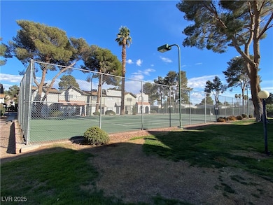View of sport court with fence and a yard