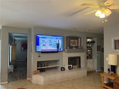 Tiled living room with baseboards, a ceiling fan,
