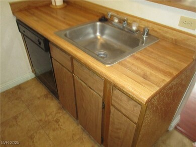Kitchen featuring brown cabinets, light countertops, dishwashing machine, and light tile patterned floors