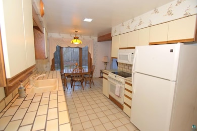 Kitchen featuring tile counters, white appliances,