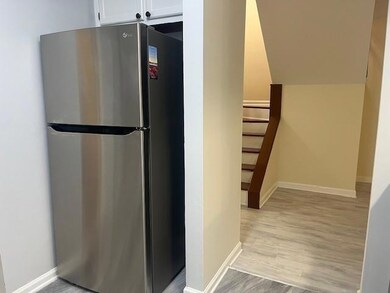 Kitchen with freestanding refrigerator, white cabinets, baseboards, and light wood-type flooring