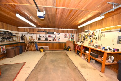 Garage featuring a workshop area, a garage door opener, wooden walls, and wooden ceiling