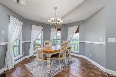 Dining room with a chandelier, baseboards, and lofted ceiling