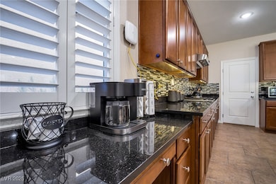 Kitchen featuring backsplash, dark stone counterto