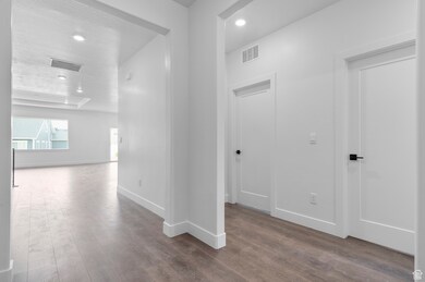 Hall with dark wood-type flooring, a textured ceiling, and recessed lighting