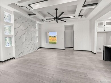 Spare room featuring ceiling fan, coffered ceiling, light wood-type flooring, and beam ceiling