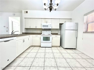 Kitchen with dark countertops, a sink, white appli