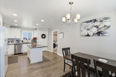 Kitchen with white cabinetry, pendant lighting, a center island, dishwasher, and light wood-style floors