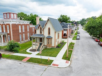 View of front of property with roof with shingles, a front yard, and a chimney