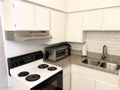 Kitchen with decorative backsplash, range with electric stovetop, a sink, and under cabinet range hood
