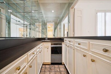 The wet bar features an ice machine, stylish mirrored walls with shelving, brick flooring, and plenty of storage. the perfect accent!