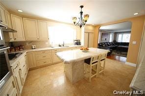 Kitchen with light countertops, pendant lighting, recessed lighting, a kitchen breakfast bar, and a kitchen island