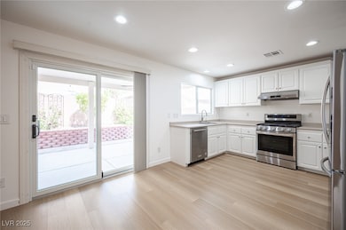Kitchen with white cabinetry, stainless steel appliances, light wood-style floors, recessed lighting, and light countertops