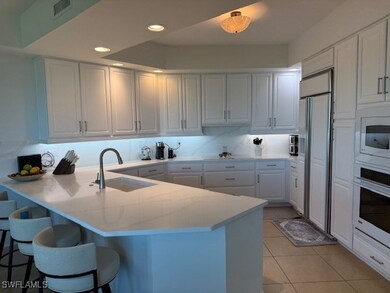 Kitchen featuring a peninsula, white cabinetry, light tile patterned floors, white oven, and paneled built in refrigerator
