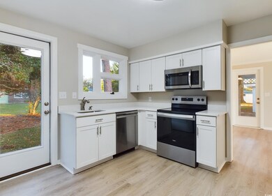 Kitchen featuring white cabinetry, sink, and stainless steel appliances, quartz countertops