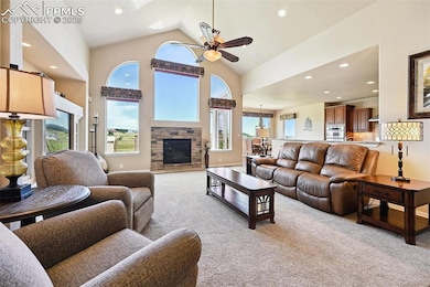 Living area with light carpet, ceiling fan, recessed lighting, a fireplace, and high vaulted ceiling