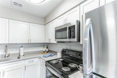 Kitchen with sink, white cabinets, appliances with