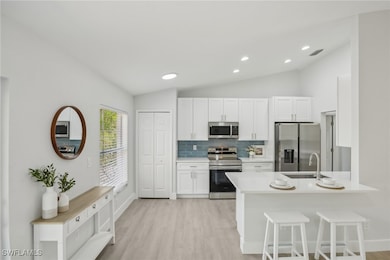 Kitchen with white cabinets, appliances with stain
