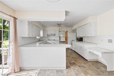 Kitchen with backsplash, appliances with stainless steel finishes, tile floors, and white cabinets