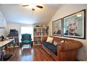 Living area featuring vaulted ceiling, dark wood-style floors, and a ceiling fan