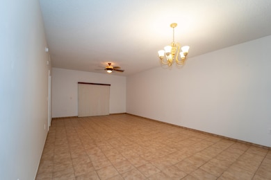 Empty room featuring ceiling fan and a chandelier