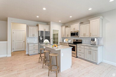 Kitchen with appliances with stainless steel finishes, tasteful backsplash, a kitchen island with sink, a kitchen breakfast bar, and recessed lighting