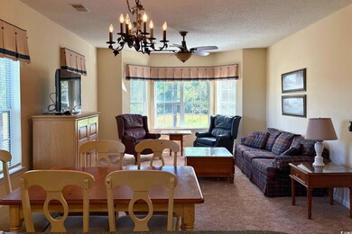 Dining room featuring plenty of natural light, carpet flooring, a textured ceiling, a chandelier, and a ceiling fan