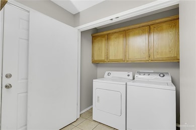 Laundry area with cabinet space, separate washer and dryer, and light tile patterned floors