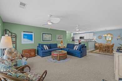 Living area with light colored carpet, ceiling fan, a chandelier, and light tile patterned floors