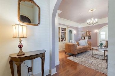 Living area with arched walkways, wood finished floors, built in features, and a chandelier
