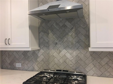 Kitchen featuring under cabinet range hood, white 