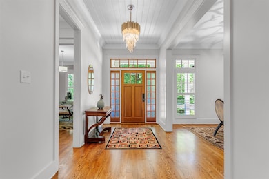 Foyer featuring wood finished floors, a chandelier, crown molding, wooden ceiling with exposed beams, and baseboards