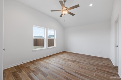 Unfurnished room featuring vaulted ceiling, a ceiling fan, wood finished floors, baseboards, and recessed lighting
