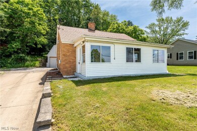 View of front of property with a front yard, a garage, and an outdoor structure