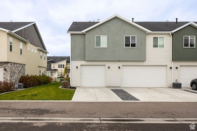Traditional-style home with a front yard, a garage, concrete driveway, and stucco siding
