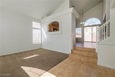 Unfurnished room with light carpet, high vaulted ceiling, light tile patterned floors, a chandelier, and stairway