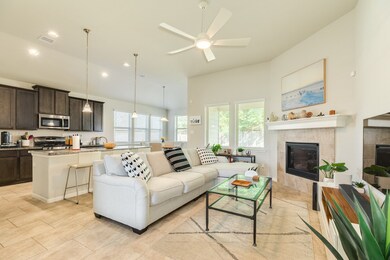 This bright open living space features a cozy fireplace, modern ceiling fan and connects seamlessly with the kitchen and dining area.