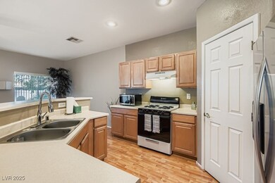 Kitchen featuring stainless steel appliances, light countertops, light wood-style floors, under cabinet range hood, and recessed lighting