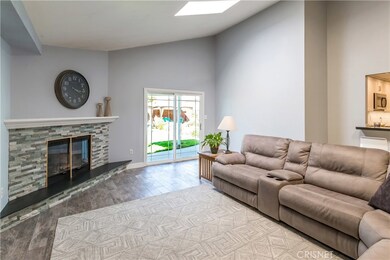 Family room with sloped ceilings, impeccable tile flooring, dual pane slider to yard and gorgeous fireplace at the center
