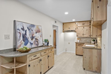 Kitchen with light brown cabinetry, recessed ligh