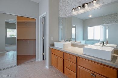 Bathroom with double vanity, light tile patterned floors, a walk in closet, and a stall shower