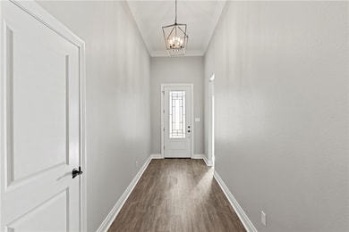 Doorway featuring crown molding, wood finished floors, and a chandelier