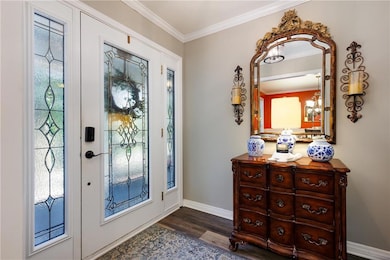 Entryway with ornamental molding, plenty of natural light, and dark wood-type flooring
