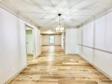 Unfurnished dining area featuring a textured ceiling, light wood-type flooring, ornamental molding, and a chandelier