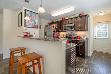 Kitchen with dark wood finished floors, dark brown cabinetry, a kitchen breakfast bar, and a peninsula