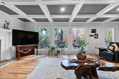 Living room featuring light wood-style flooring, crown molding, beamed ceiling, and coffered ceiling