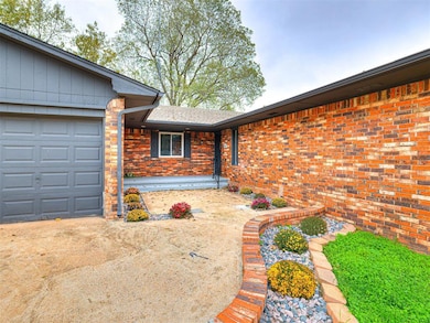 View of exterior entry with brick siding, a patio, and a garage