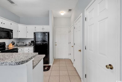 Kitchen with white cabinetry, black appliances, an