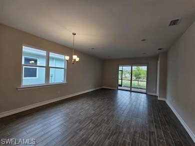 Unfurnished room with dark wood-style floors, a ch