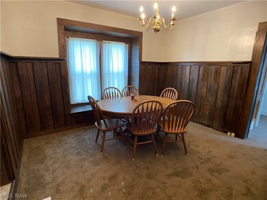 Carpeted dining space with a notable chandelier and crown molding